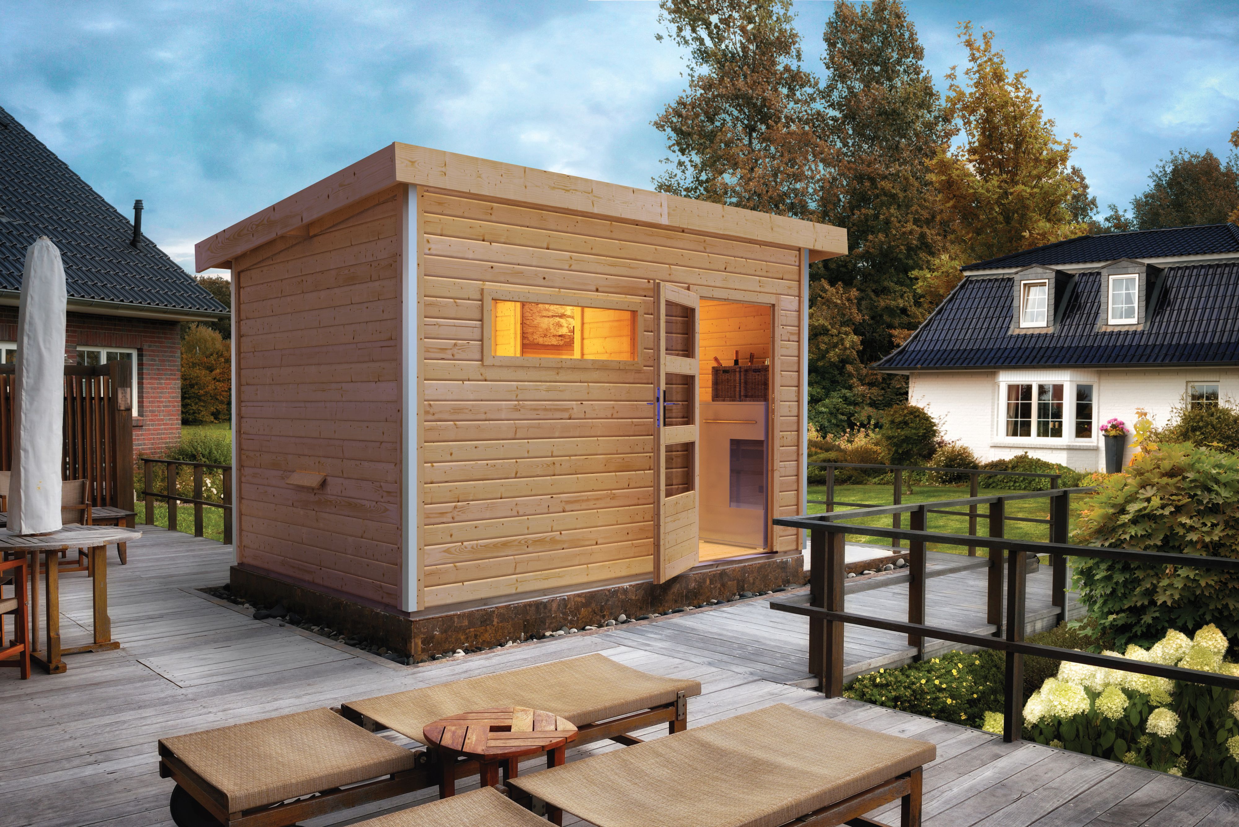Karibu Saunahaus Skrollan 2 mit Vorraum als Gartensauna aus Massivholz im Garten mit Glasfront